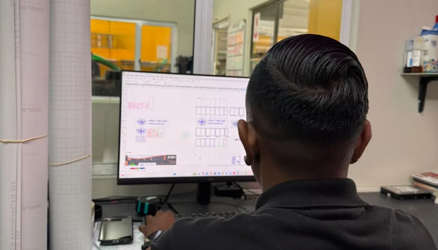 Umhlanga Signs designer setting out signage artwork on screen with vinyl colour swatches at the Glen Anil studio