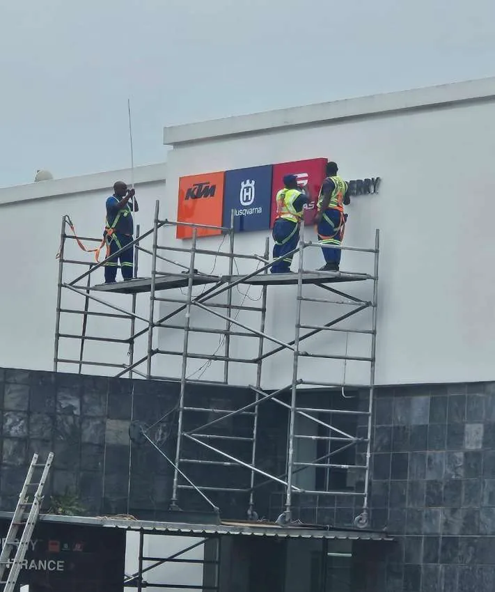 Umhlanga Signs installers fitting dealership signage from scaffolding